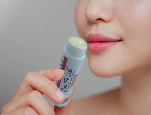 a woman puts on our lips from our balm with CBD extract with a tropical scent 